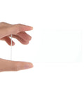 Hand holding clear glass cover from Hella Tough 10 Pack Welding Lens Clear Glass Outer Covers High Definition Spark Blockers.