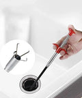 Hand using slim flexible grabber tool to unclog kitchen sink drain