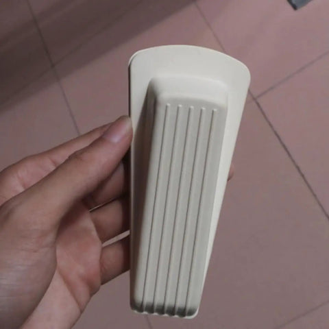 Close-up of hand holding a white rubber door stopper, part of 5 Pack Door Wedge Stoppers Rubber Anti Skid Prevent Slamming For Home And Office.