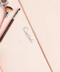 Heavy Duty Stainless Steel Cotter Pins With Wavy Design Secure Industrial Hitch Connections And Mechanical Fasteners That Never Slack Or Fail For Serious Projects on a pink background with makeup tools.