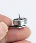 Close-up of 1103 Beefy High Speed Brushless Motor 15000KV for RC Drones held between fingers, silver outer rotor design
