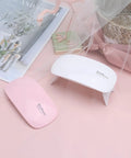 Mini Portable UV LED Nail Dryer Lamp 6W Quick Cure Curing Light For Gel Nail Polish And Natural Nails displayed on a pink background.
