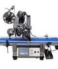 Industrial Grade Automatic Flat Surface Label Applicator With Touchscreen Control And Auto Photo Sensor view from the side on blue conveyor.