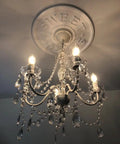 Original Brink House 5 Light Crystal White Chandelier, hardwired flush mount with white metal frame, lit in a dim interior space.