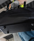 Person carrying Heavy Duty Black Canvas Tool Bag With Wide Mouth Opening Leather Handles 12 Inch Tool Tote Vinyl Bottom