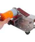 Uonlytech Mini Bidirectional Electric Belt Sander Grinder With Strong Copper Motor showing hand holding the motor, compact design for hobby workshop use.