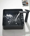 Sleek Matte Black Rectangle Vessel Sink 14 By 14 Inch Above Counter Vanity With Porcelain Ceramic Low Water Absorption Acid Resistant Easy To Clean Surface Durable Modern Bathroom Vessel Sink With Black Pop Up Drain filled with flowing water