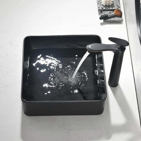 Sleek Matte Black Rectangle Vessel Sink 14 By 14 Inch Above Counter Vanity With Porcelain Ceramic Low Water Absorption Acid Resistant Easy To Clean Surface Durable Modern Bathroom Vessel Sink With Black Pop Up Drain filled with flowing water