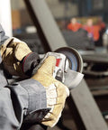 Worker using Beefy Torque 5 Inch Variable Speed Angle Grinder With Electronic Speed Control in a workshop setting, close-up view.