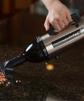 Evolution Hand Vacuum Portable 120V 504W With All Steel Construction For Dry Pickup At Home Office Or Car Satin Nickel Black Ultra Powerful Yet Lightweight For Quick Cleanups Everywhere, shown in use on a kitchen counter picking up cereal.
