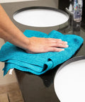 Hand cleaning a countertop with Blue Virgin Huck Cotton Rags 25 Inch By 16 Inch Lint Free Cleaning Cloths, 50 Pound Box, 5 To 7 Pieces Per Pound, Workhorse Wipe Down Rags For Auto Shop And Home Use.