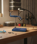Rock Your Fly Tying Game With This Premium Hardened Steel Vise Featuring A Non Slip Adjustable Head And Precision Grip For Bench Work Scaling And Detailed Hobby Builds on a wooden workbench with feathers and threads.