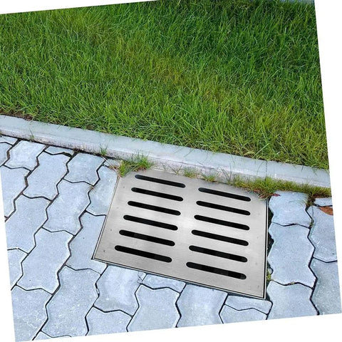 Heavy Duty 304 Stainless Steel Shower Drain Cover installed in outdoor patio area with grass and pavers.