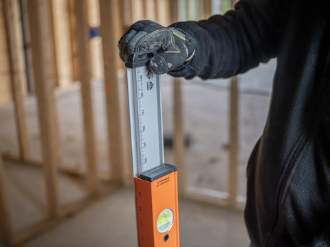 Hefty 48 To 80 Inch Telescoping Box Beam Level With Lock Tight Extension and Legit Precision Edges held by a gloved hand on a job site.