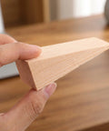 Close-up of hand holding Built Tough Heavy Duty Wooden Door Wedge Stopper 20 Pack Triangular Wall Protector for home use