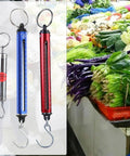 Rock Solid Mechanical Spring Scale With Hanging Hook Dynamometer Accurate Force Gauge Up To Fifteen Kilos Portable Aluminum Alloy scales displayed among fresh vegetables.