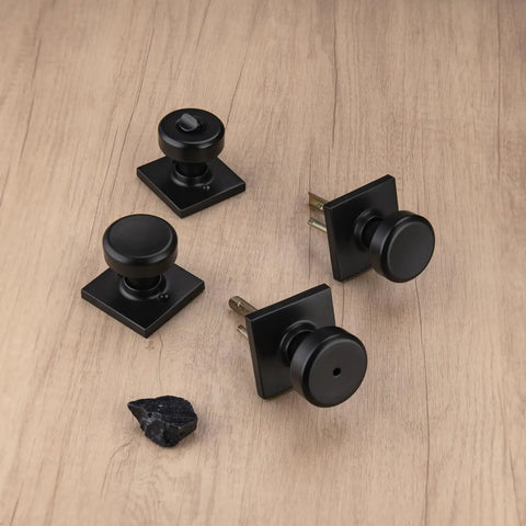 Slick Matte Black Privacy Door Knobs With Dang Solid Lock Function And Clean Square Aluminum Rosette, Six Pack displayed on wood.
