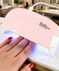 Mini Portable UV LED Nail Dryer Lamp 6W quick cure lamp in pink with hand curing gel nails on a marble surface.