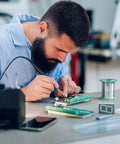 Person soldering on a Double Sided FR-4 PCB Board Kit Four Pack Perfect Starter Bangin Prototyping Boards With 0.1 Inch Pitch 2.54mm Holes