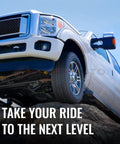 White truck climbing over rocky terrain against clear sky
