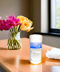 Jar of disinfectant wipes on a wooden table beside a vase of flowers and a folded towel in natural light.