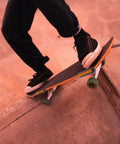 A person skateboarding on a ramp with visible reflective strips on the skateboard's side.