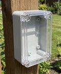 Rock Solid 6 Pack Abs Electrical Junction Box Enclosure With Crystal Clear Covers for Easy Wiring mounted on a wooden post.