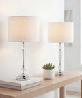 27 Inch Clear Crystal LED Table Lamp Set of 2 for Living Room or Bedroom on a wooden table, featuring chrome candlestick base and white linen shade.
