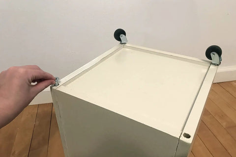 Installation of Heavy Duty Black Plastic Swivel Casters Four Pack With Ball Bearing Wheels And Brass Stem Mounts on furniture.