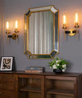 Antique Bronze Two Light Sconce For Bathroom Vanity With Dual Two Point Eight Inch Cylinder Glass Shades beside a mirror