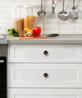 Rustic Forest Mushroom Cabinet Knobs 4 Pack on white kitchen drawers with vegetables and utensils on countertop.