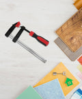 Solid Heavy Duty 6 Inch Metal Bar Clamp With Quick F Handle Adjusts Fast For One Hand Woodworking DIY Welding Rust Proof Construction Projects on a work table.