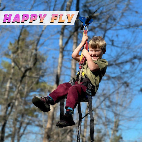 Child enjoying Backyard Zipline Kit For Kids And Adults With Stainless Steel Spring Brake in a sunny garden setting.