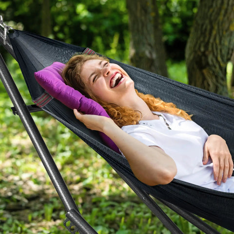Woman relaxing in black Universal Hammock Stand 600 Lb Capacity, 30 Second Foldable Setup, No Tools Or Screws Needed, Portable Camping Hammock Stand With 3 Year Warranty, Heavy Duty Steel Frame For Indoor Outdoor Use, Black
