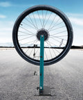 Professional Bicycle Wheel Truing Stand Removable Multifunction Wheel Alignment Tool Fits 16 To 29 Inch Mountain Bikes And 700c Road Bikes For Rim Calibration And Maintenance with a wheel on an outdoor road