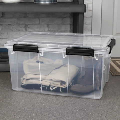 Rock Solid Clear Stackable Plastic Storage Bins With Resilient Gasket Seals holding clothes and boots on a shelf in a garage.