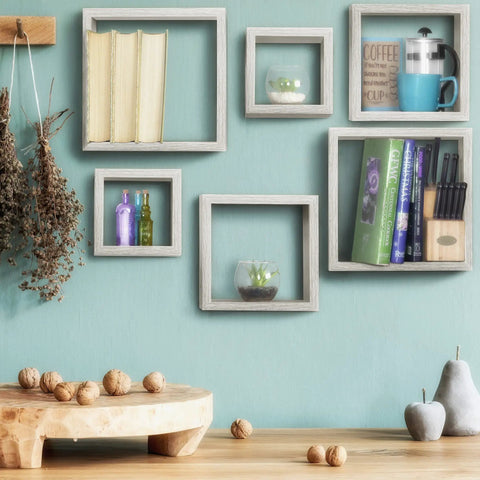 Slick Multi Size Floating Wall Shelves In Weathered Grey display various items, including books and decor, arranged decoratively.