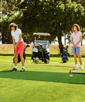 Individuals golfing on Indoor Outdoor 3x10ft Golf Putting Green Mat With Thick 10mm Non Slip Base And Side Borders Portable Three Hole Design Movable Cup For Home Backyard Or Office Practice Realistic Turf outdoors