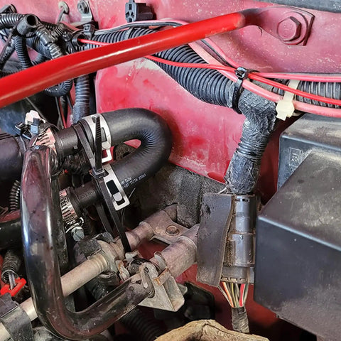 Close-up of a Universal Engine Heater Core Bypass Kit With Flexible Hoses for quick coolant fix in vehicle engine compartment.