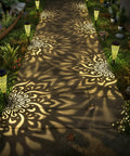 Pathway illuminated by Six Pack Solar Outdoor Garden Lights With Mandala Pattern, Warm Amber Glow, Waterproof, in black.