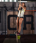 Woman climbing a rope in gym, showcasing athleticism, perfect for Built Like A Tank Wall And Ceiling Mount Bracket for Suspension Straps.
