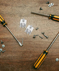 Stainless Steel Fridge Shelf Support Clips 8 Pack With Brushed Finish next to screwdrivers and screws on wooden surface