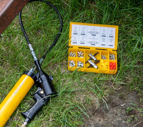 LockNLube grease fitting multi-tool kit in yellow case; opened to reveal assorted metal fittings and large grease gun