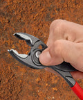Hand using Slim Front And Side Grip Pliers With Box Joint And Push Button Adjustment For Tight Spots, 200 Mm on rusted surface