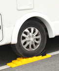 RV tire on yellow interlocking camper leveling blocks kit with anti slip ramps 10 pack includes one wheel chock and handy carrying bag for travel trailer and RV no slip rock solid stabilization on uneven ground